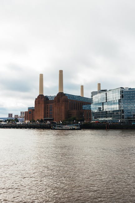 A view of the Battersea Power Station rooftop garden, featuring neatly maintained lawn areas with trimmed grass and garden beds arranged along the edges. The garden includes a variety of plants and sh